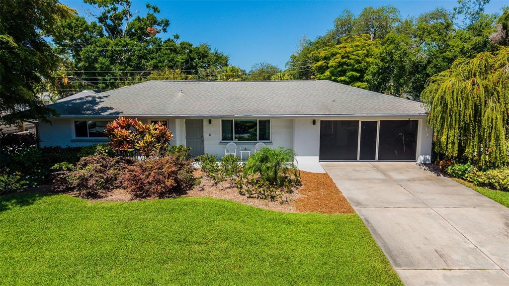 A single-story white house with a gray shingled roof, a driveway, and landscaped front yard — 2747 JEFFERSON CIRCLE, SARASOTA, FL
