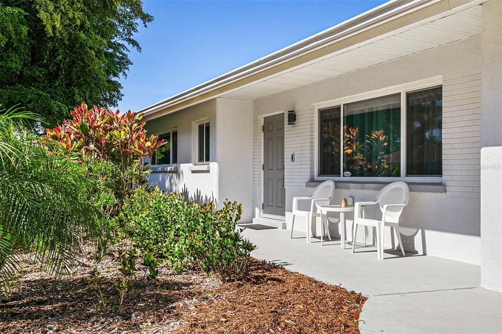 A white house exterior features a gray front door, a large window, and two chairs — 2747 JEFFERSON CIRCLE, SARASOTA, FL