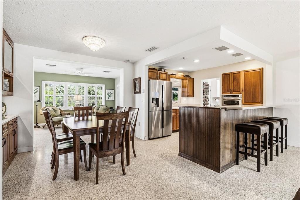 A kitchen and dining area featuring wooden cabinets, a breakfast bar, and speckled flooring — 2747 JEFFERSON CIRCLE, SARASOTA, FL