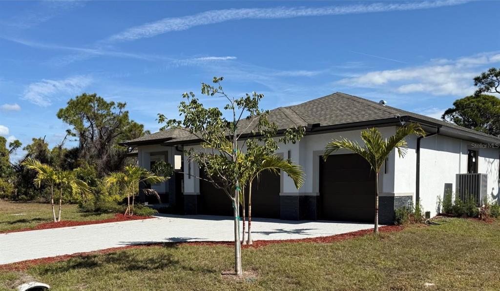 A single-story house with a white exterior, dark garage doors, and a paved driveway — 47 BRIG CIRCLE E, PLACIDA, FL
