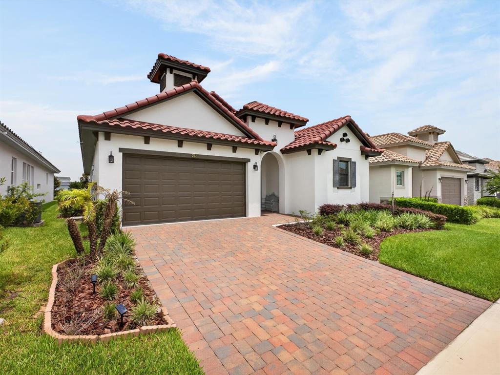 A single-story house with a brown garage door, tiled roof, and a brick paver driveway — 268 HAMPTON LOOP, DAVENPORT, FL