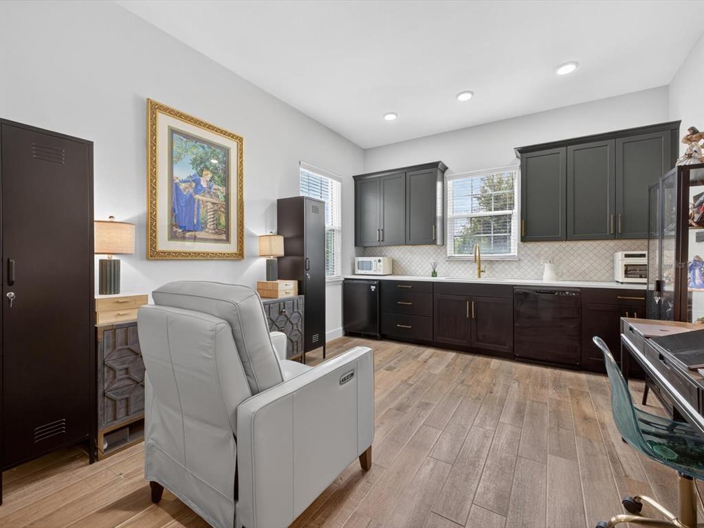 A room featuring dark cabinetry, a light gray armchair, and wood-look tile flooring — 268 HAMPTON LOOP, DAVENPORT, FL