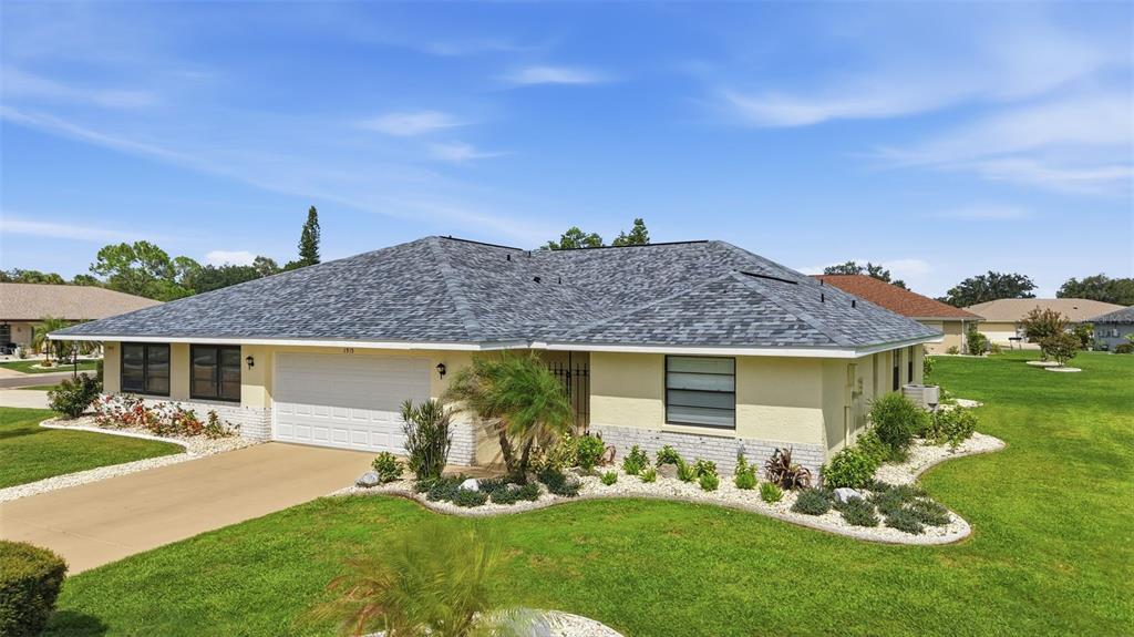 A single-story house with a light yellow exterior, a gray shingled roof, and a garage — 1915 W DEL WEBB BOULEVARD, SUN CITY CENTER, FL