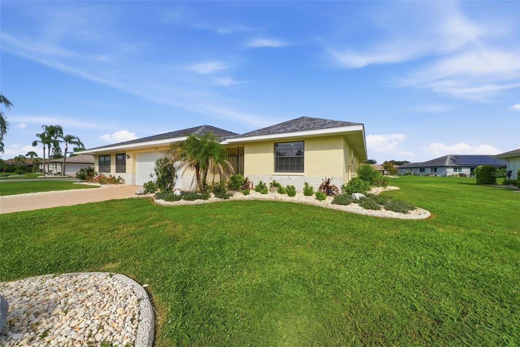 A single-story house with a yellow exterior, a two-car garage, and a landscaped front yard — 1915 W DEL WEBB BOULEVARD, SUN CITY CENTER, FL