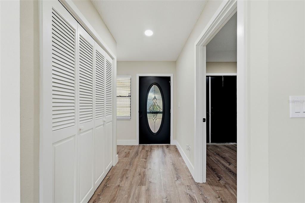 A hallway features wood-look flooring, white louvered closet doors, and a black front door — 1915 W DEL WEBB BOULEVARD, SUN CITY CENTER, FL