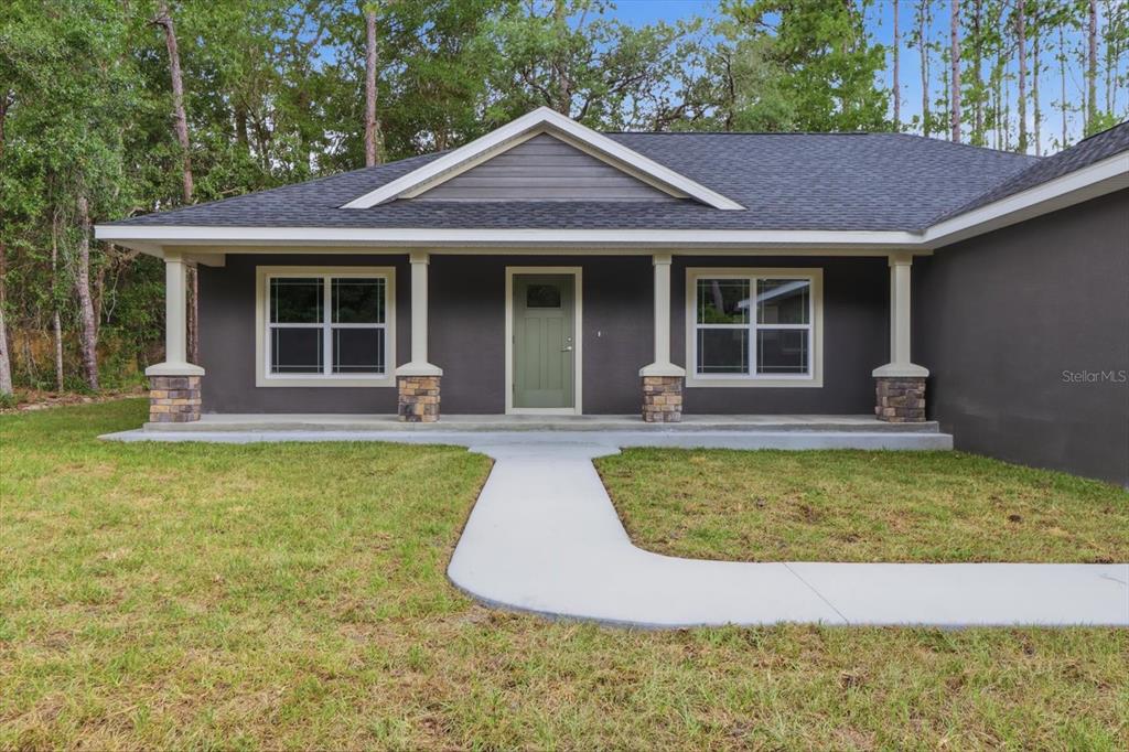 A single-story house with a dark gray exterior, stone-based columns, and a front porch — 9944 N WAYLAND AVENUE, CITRUS SPRINGS, FL