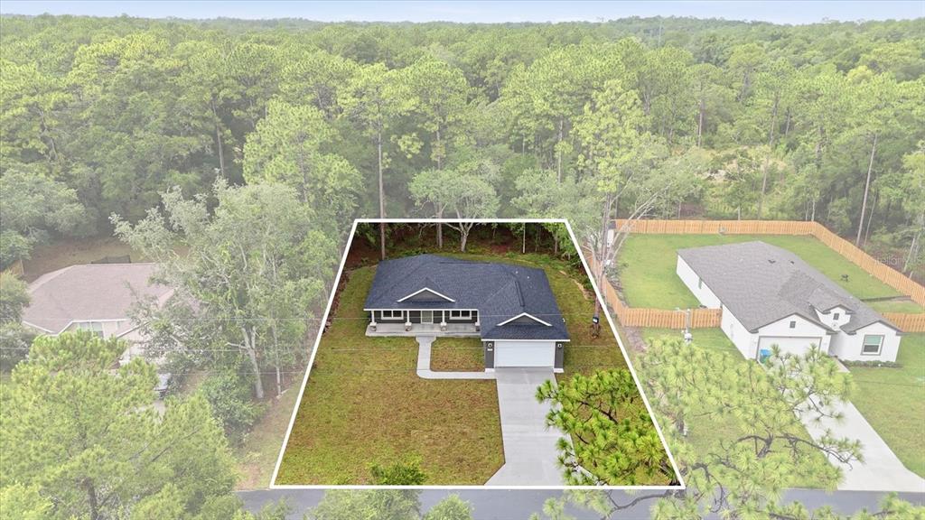 An aerial view shows a single-story house with a dark roof and a concrete driveway — 9944 N WAYLAND AVENUE, CITRUS SPRINGS, FL