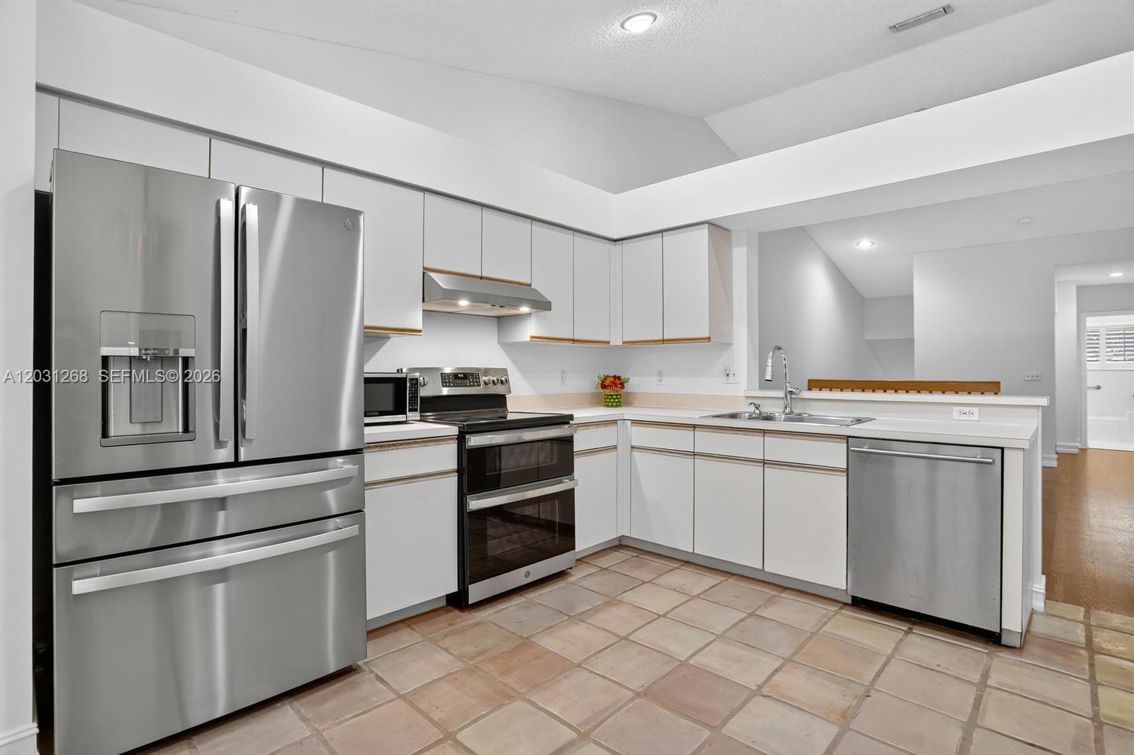 A kitchen features white flat-panel cabinets, stainless steel appliances, and light-colored square floor tiles — 7525 NW 61st Ter # 1603, Parkland FL 33067, PARKLAND, FL
