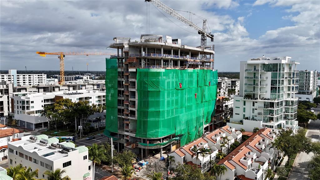 An aerial view shows a multi-story building under construction draped in green safety netting — 290 COCOANUT AVENUE UNIT 601, SARASOTA, FL