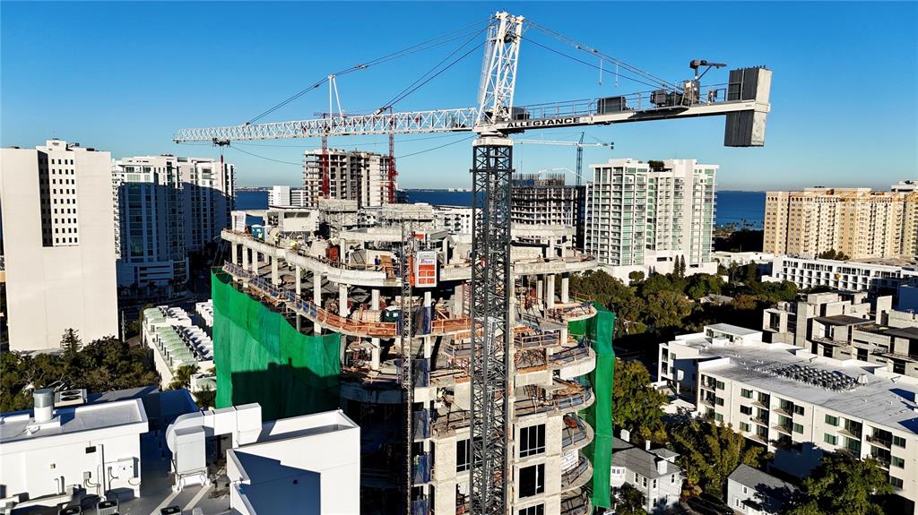 An aerial view shows a high-rise building under construction with a large crane nearby — 290 COCOANUT AVENUE UNIT 601, SARASOTA, FL