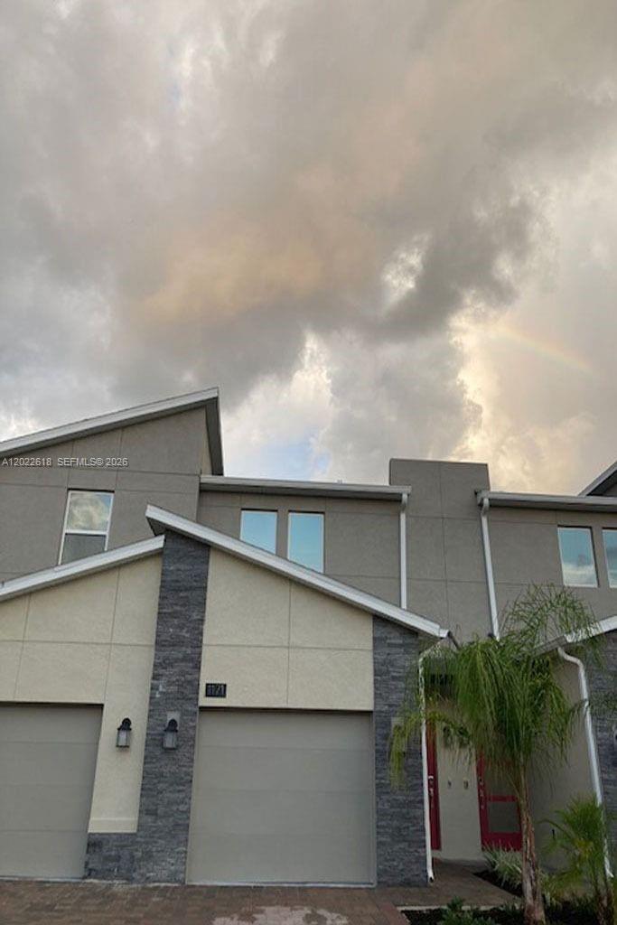 A two-story townhouse exterior with a gray facade, stone accents, and a garage — 1171 CHALLENGE DR # 1171, Davenport FL 33896, DAVENPORT, FL