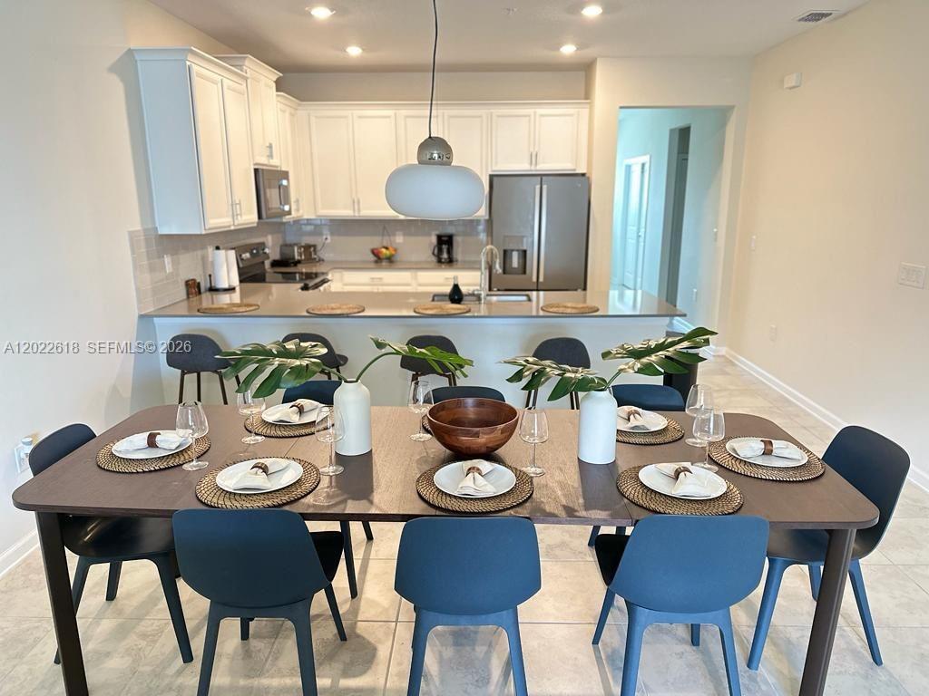 A dining area with a dark table and blue chairs sits before an open kitchen — 1171 CHALLENGE DR # 1171, Davenport FL 33896, DAVENPORT, FL