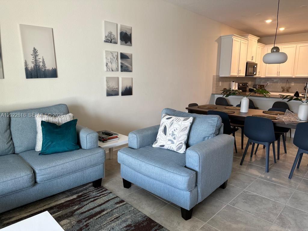 A living room with light blue furniture flows into a dining area and kitchen — 1171 CHALLENGE DR # 1171, Davenport FL 33896, DAVENPORT, FL