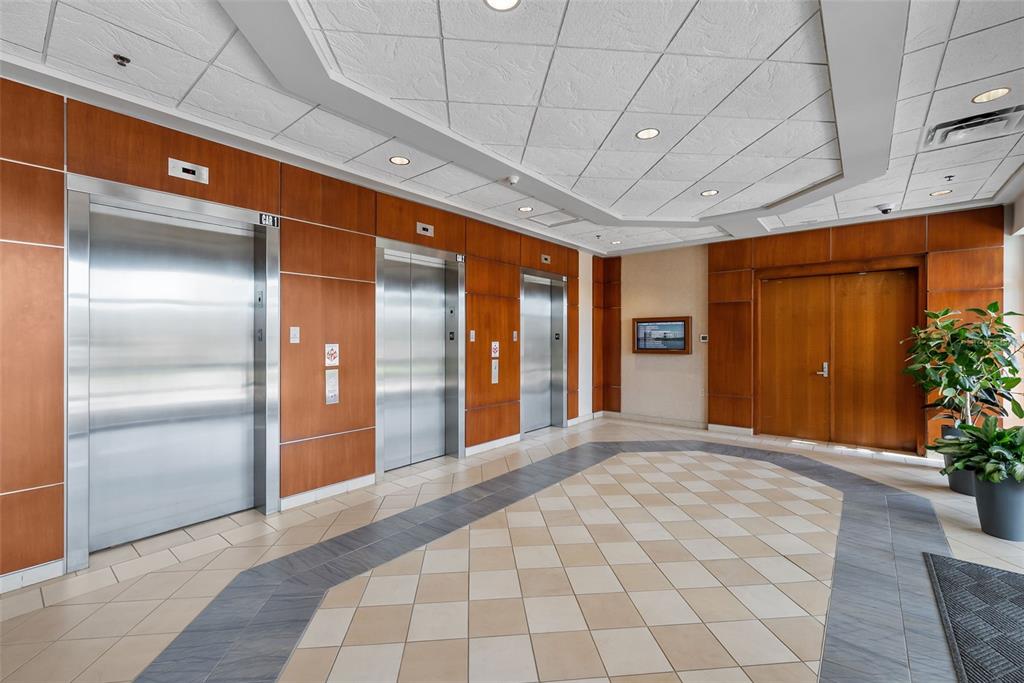 A lobby area features three stainless steel elevators, wood-paneled walls, and a tiled floor — 5550 W EXECUTIVE DRIVE UNIT 250, TAMPA, FL