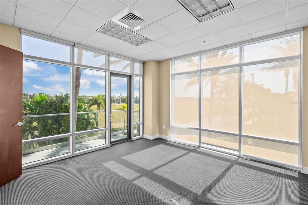 An empty office with gray carpet, drop ceiling, and floor-to-ceiling windows overlooking palm trees — 5550 W EXECUTIVE DRIVE UNIT 250, TAMPA, FL