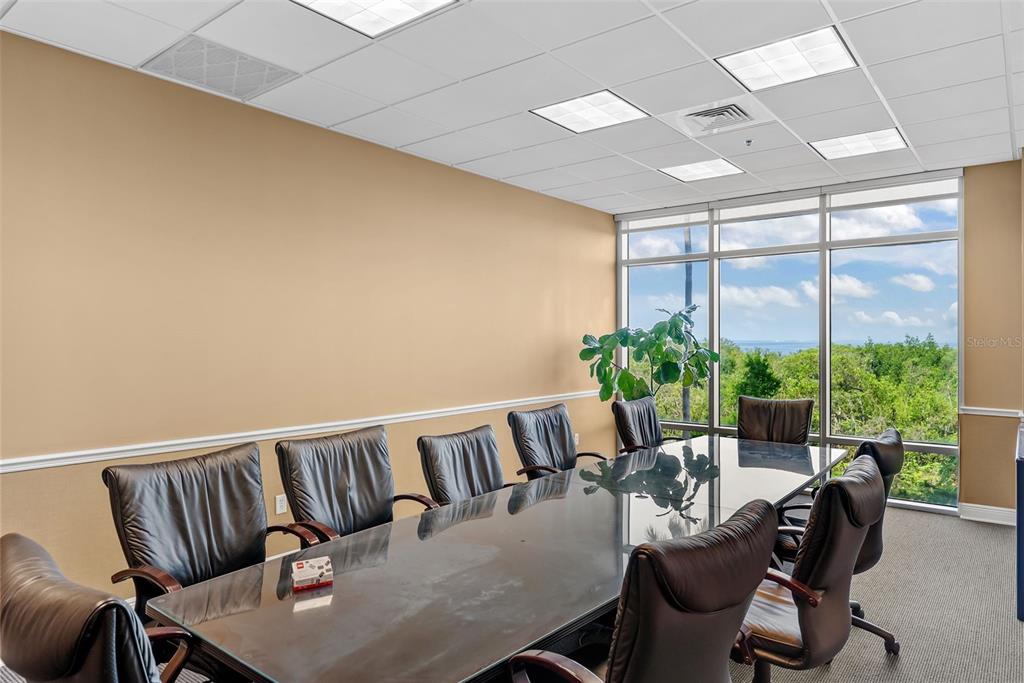 A conference room features a glass-topped table, black leather chairs, and floor-to-ceiling windows — 5550 W EXECUTIVE DRIVE UNIT 250, TAMPA, FL