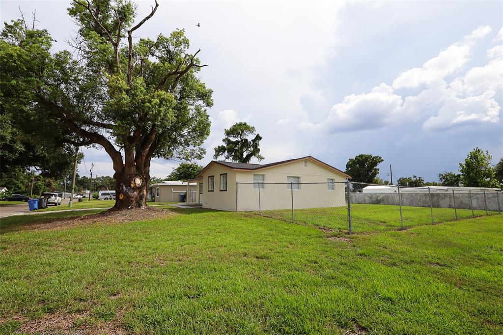 A large tree stands beside a light-colored house enclosed by a chain-link fence — 505 CLEARFIELD ROAD, BRANDON, FL
