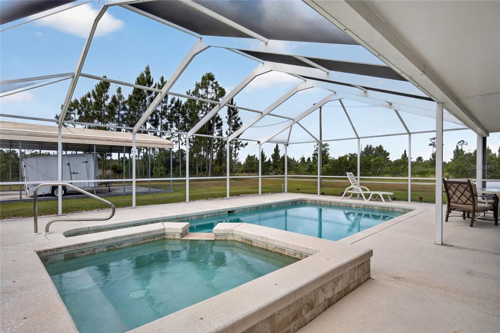 A screened-in patio features a swimming pool, a raised hot tub, and a metal carport — 8433 LIMONIA DRIVE, INDIAN LAKE ESTATES, FL