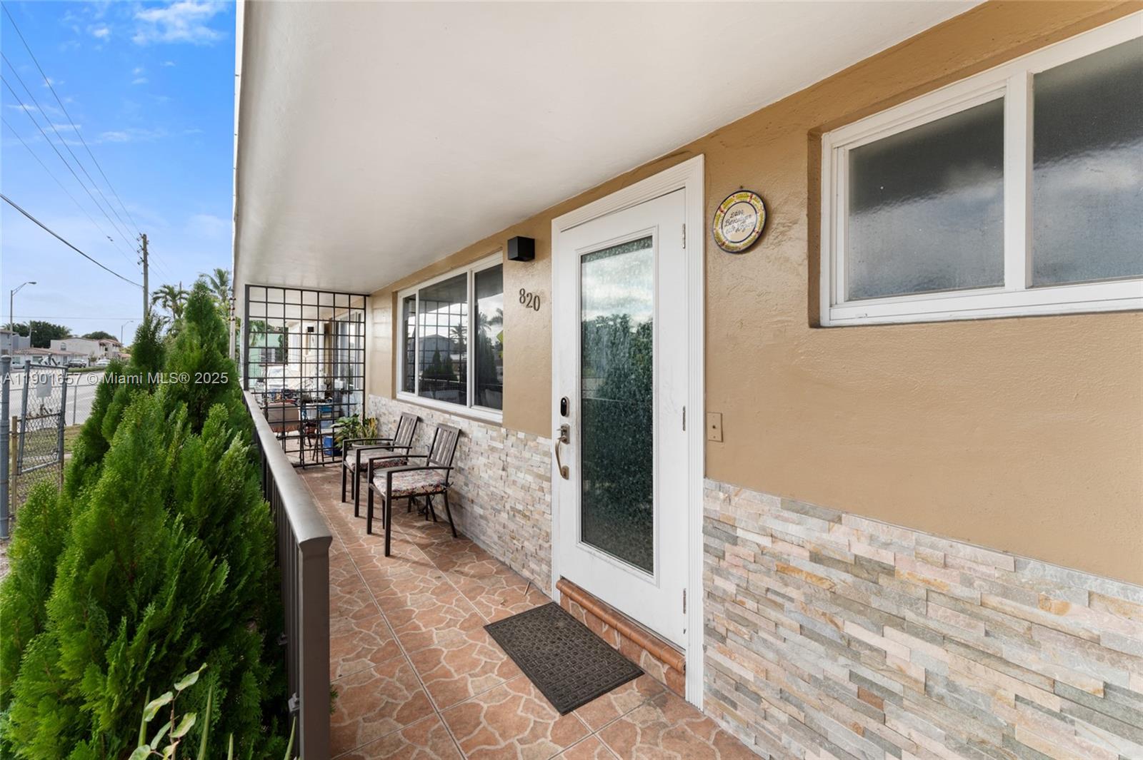 A covered outdoor patio features stone-tiled walls, a glass-paneled door, and two chairs — 820 SW 17th Ave # 1, Miami FL 33135, MIAMI, FL