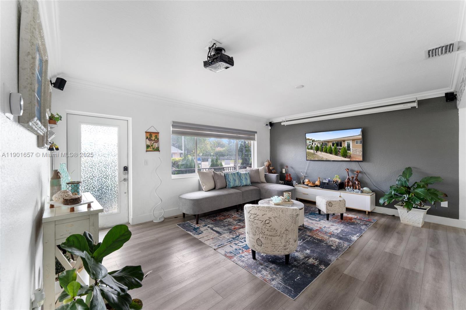 A living room features a gray sectional sofa, a projector, and a wall-mounted television — 820 SW 17th Ave # 1, Miami FL 33135, MIAMI, FL