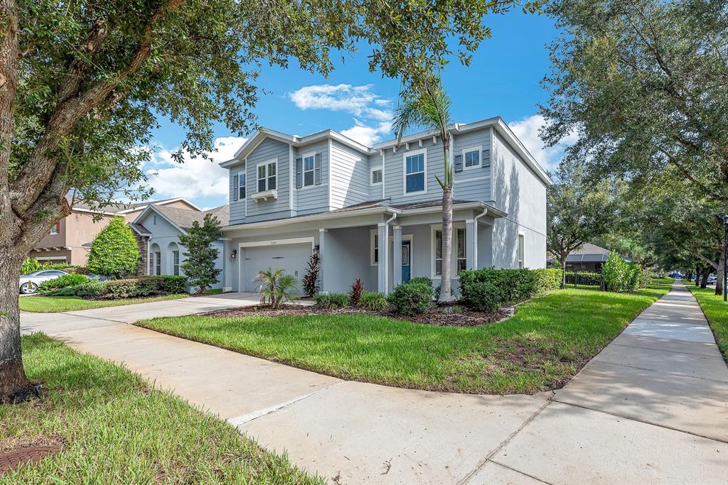 A two-story light gray house with a front-facing garage and a sidewalk in the foreground — 5101 SANDERLING RIDGE DRIVE, LITHIA, FL