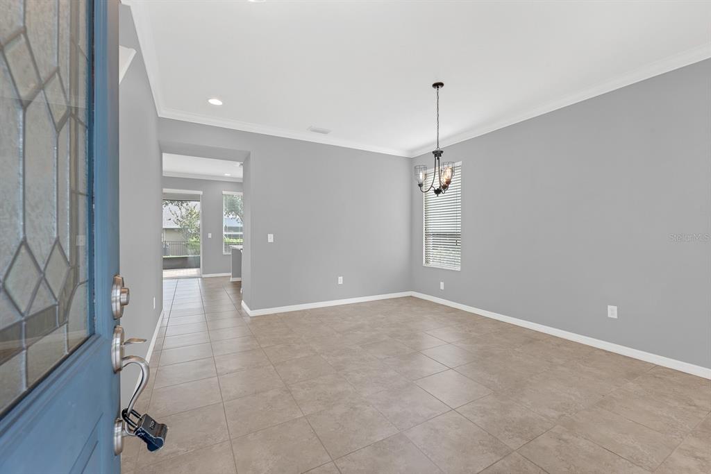 A dining room with gray walls, tile flooring, a chandelier, and a view into a hallway — 5101 SANDERLING RIDGE DRIVE, LITHIA, FL