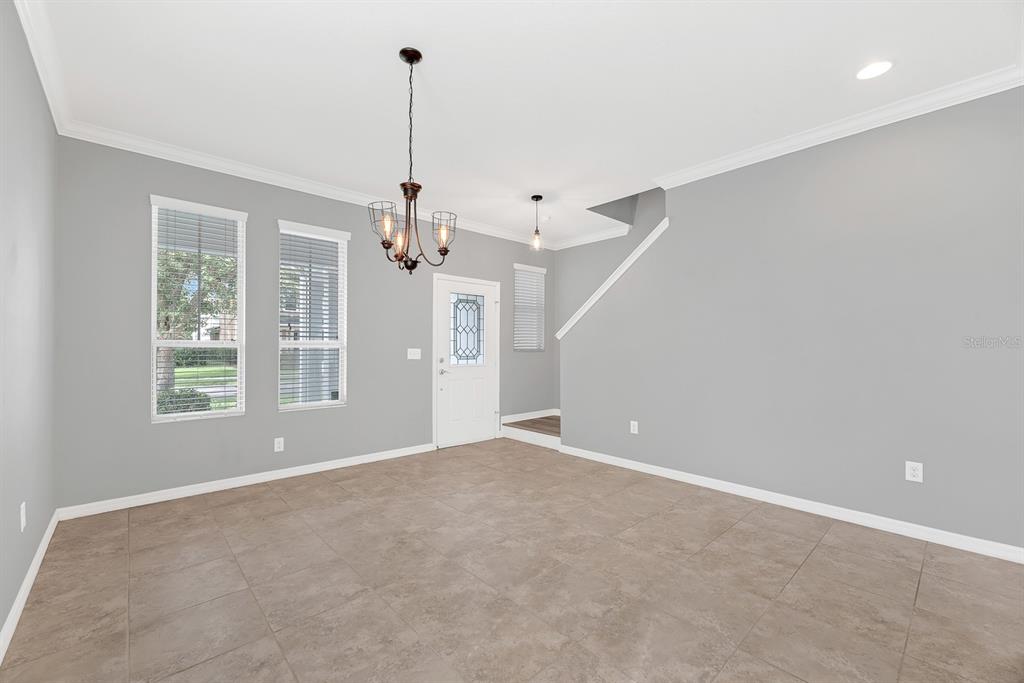 An empty room with gray walls, tile flooring, a chandelier, and a front door — 5101 SANDERLING RIDGE DRIVE, LITHIA, FL