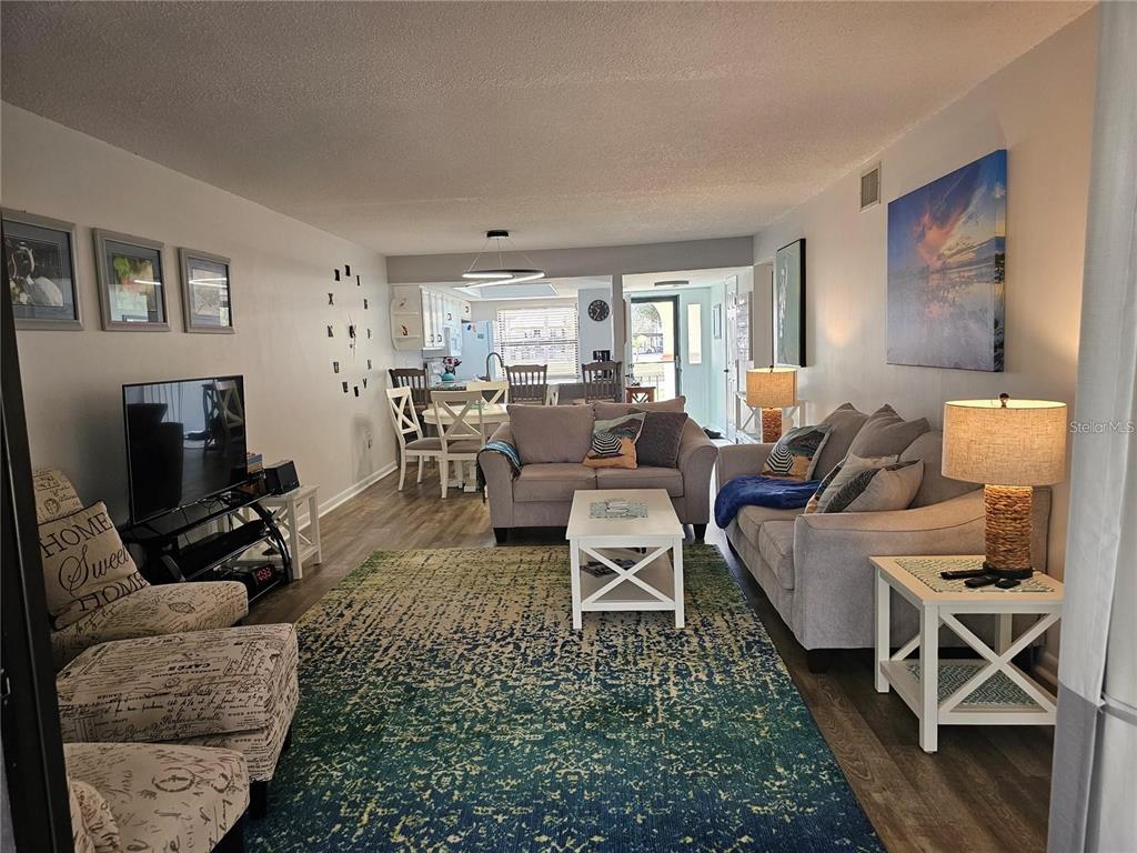 A living room with light gray sofas, a patterned rug, and an open-concept dining area — 2104 GRANADA COURT, LAKE WALES, FL