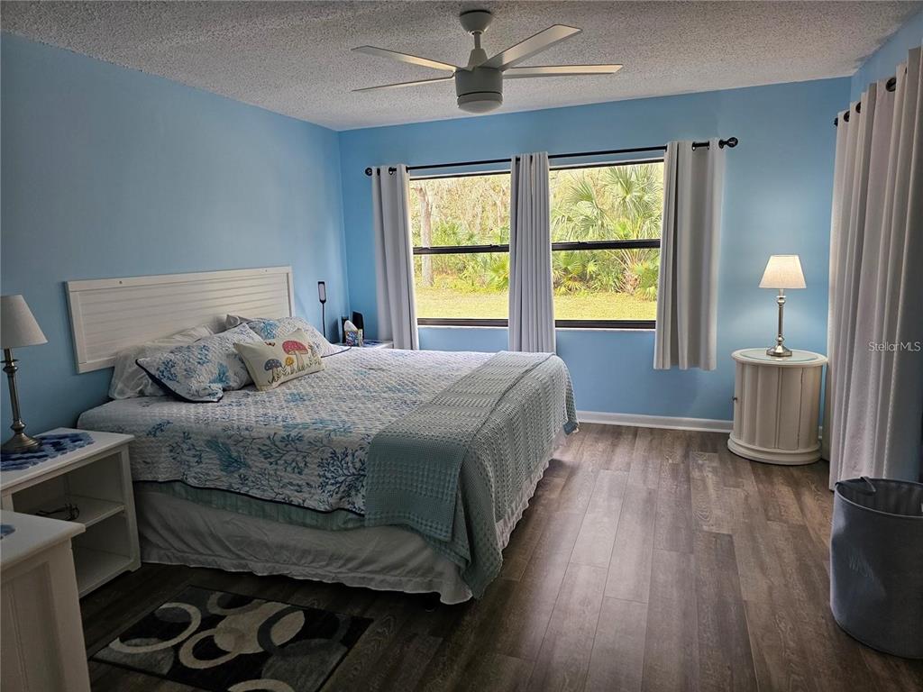 A bedroom features light blue walls, a king bed, wood-look flooring, and two windows — 2104 GRANADA COURT, LAKE WALES, FL