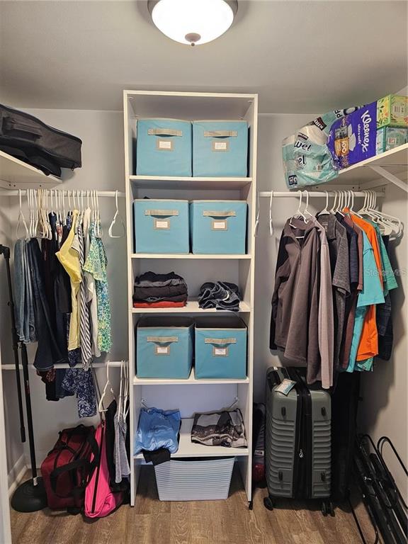 A walk-in closet features a central white shelving unit, hanging clothes, and storage bins — 2104 GRANADA COURT, LAKE WALES, FL