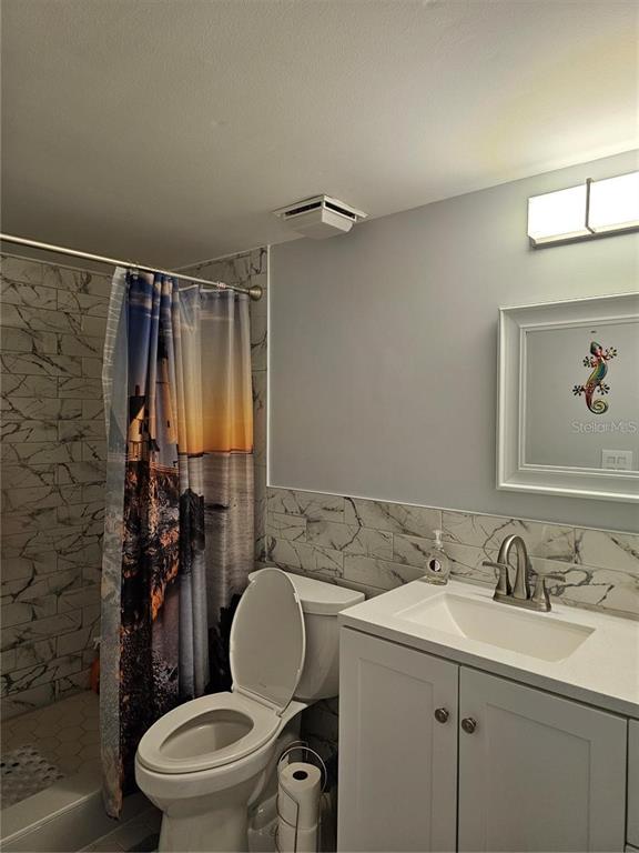 A bathroom features a marble-tiled shower, a white vanity, and a toilet — 2104 GRANADA COURT, LAKE WALES, FL