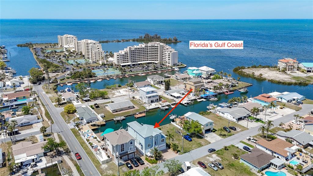 An aerial view shows a light blue house with a metal roof near a canal — 13737 VICTOR AVENUE, HUDSON, FL