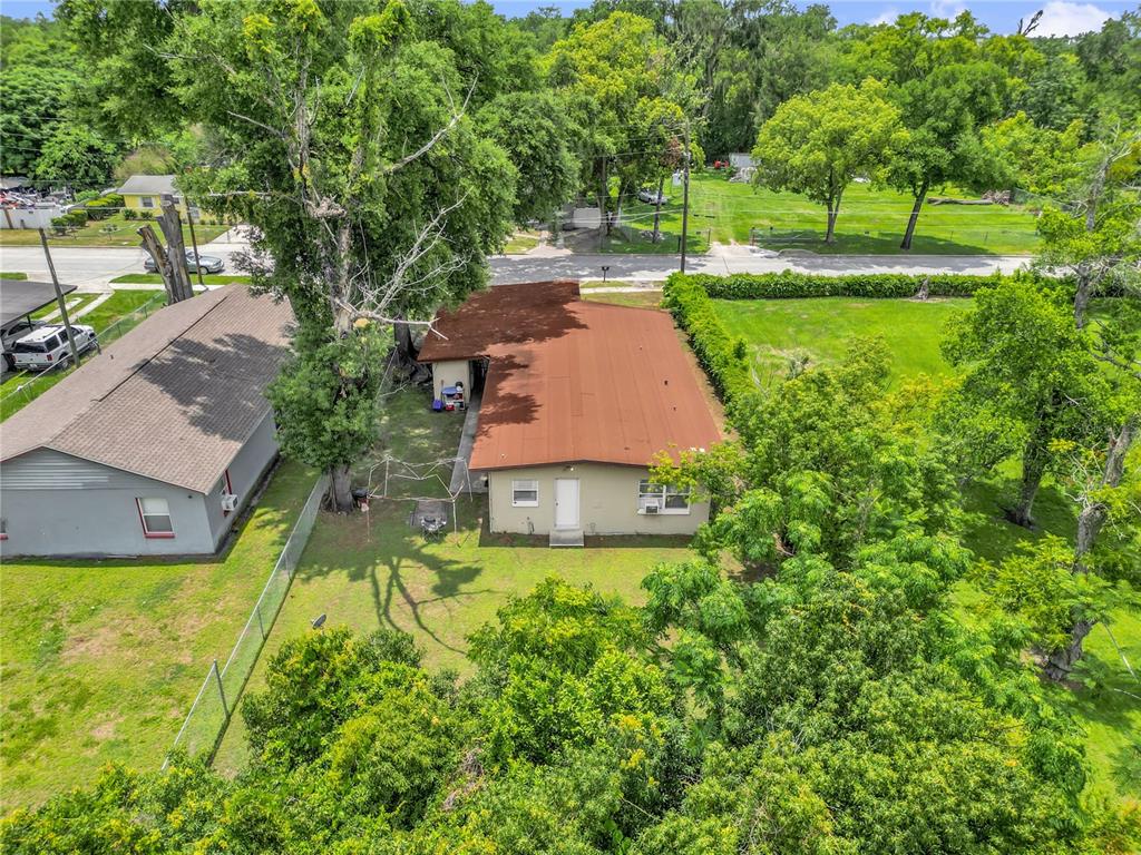 An aerial view shows a single-story house with a brown roof surrounded by green trees — 1113 S LEE AVENUE, ORLANDO, FL