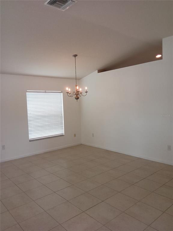 A dining room with tile flooring, a chandelier, and a window with blinds — 7733 OUTERBRIDGE STREET, WESLEY CHAPEL, FL