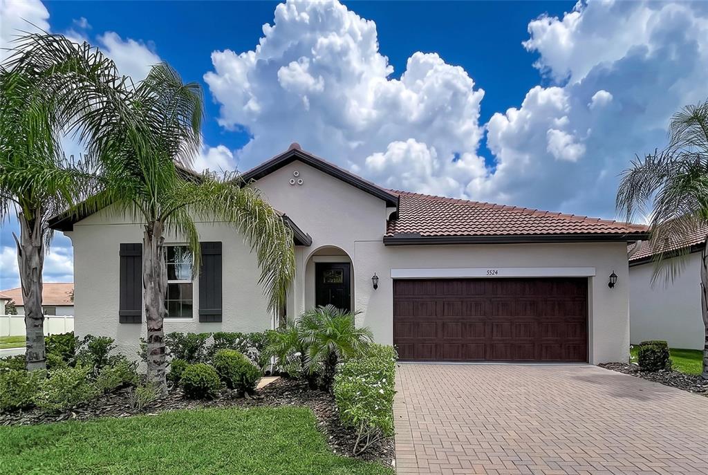 A single-story house with a tiled roof, a two-car garage, and palm trees in front — 5524 LITTLE PATH DRIVE, WIMAUMA, FL