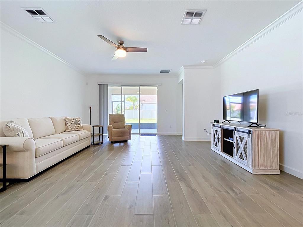 A living room features a beige sofa, a television on a wooden stand, and tile flooring — 5524 LITTLE PATH DRIVE, WIMAUMA, FL