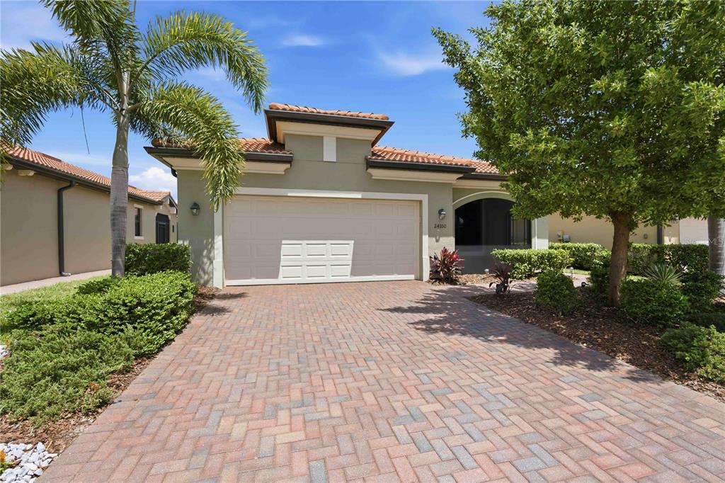 A single-story house with a paved driveway, a two-car garage, and a palm tree — 24100 SPARTINA DRIVE, VENICE, FL