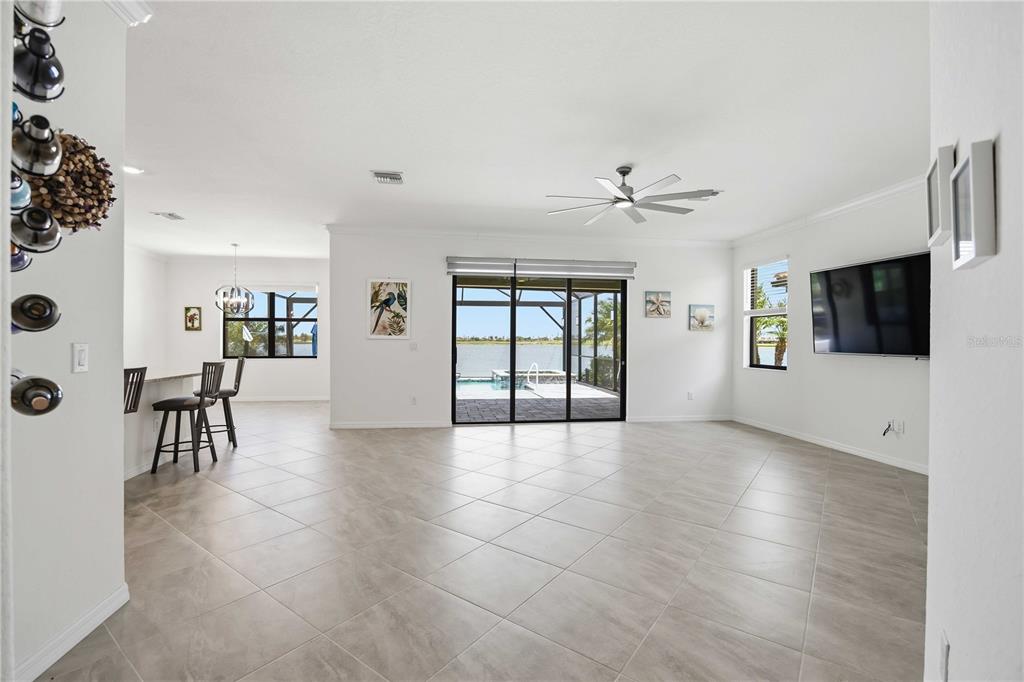 A bright, open-concept living area features large tile floors, a ceiling fan, and sliding glass doors — 24100 SPARTINA DRIVE, VENICE, FL