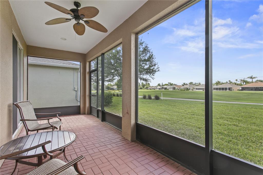 A screened-in patio with a brick floor, ceiling fan, and a view of a golf course — 29255 GRASS BUNKER DRIVE, SAN ANTONIO, FL