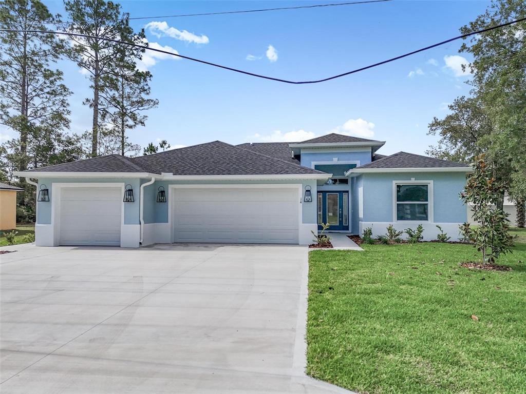 A light blue single-story house features a three-car garage and a concrete driveway — 14 WHITE BIRCH LANE, PALM COAST, FL