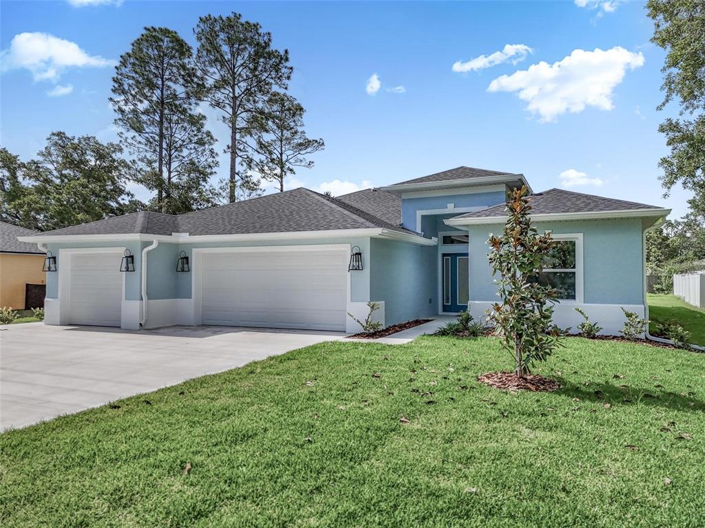 A light blue single-story house with a three-car garage and a front lawn — 14 WHITE BIRCH LANE, PALM COAST, FL