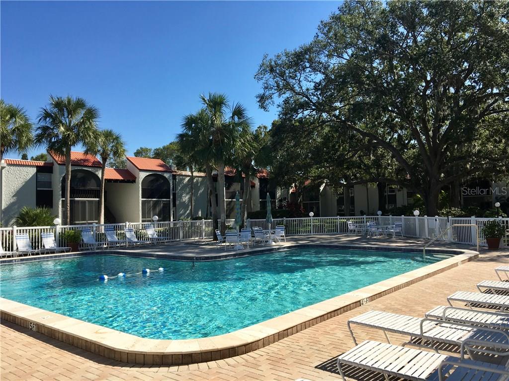 A swimming pool with lounge chairs sits in front of a multi-story apartment building — 3213 BENEVA ROAD UNIT 204, SARASOTA, FL