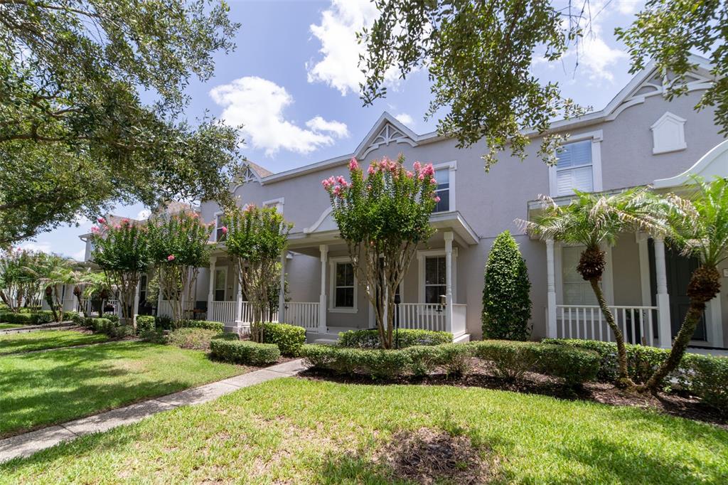 A row of two-story townhomes with front porches, manicured landscaping, and blooming crape myrtle trees — 3933 CLEARY WAY, ORLANDO, FL