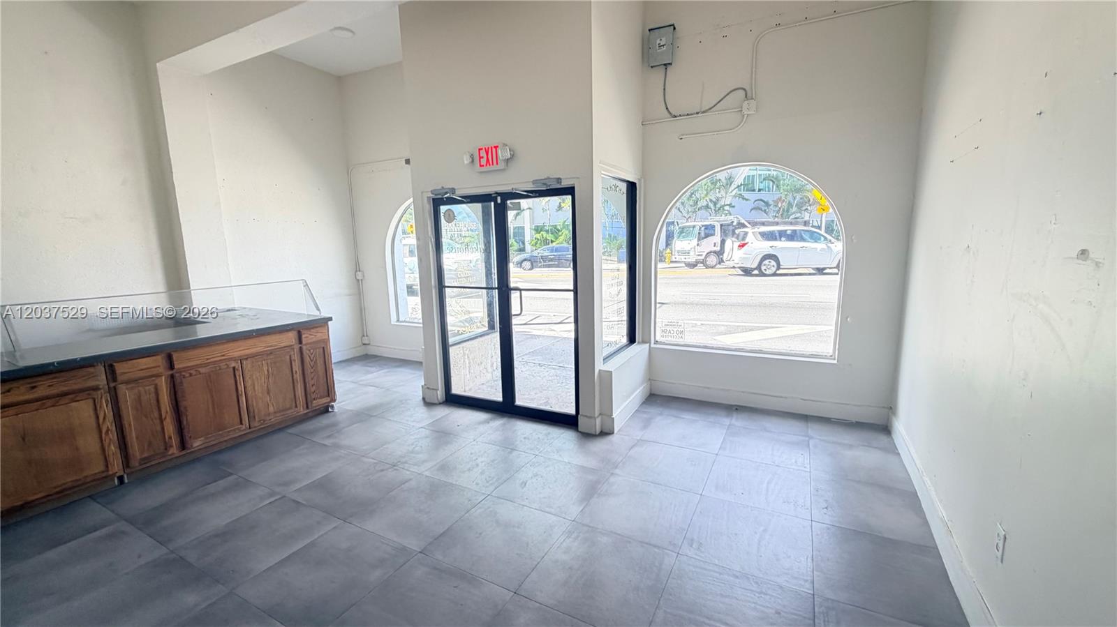 An empty commercial space features gray tile flooring, a wooden counter, and arched windows — 2614 SW 8th St # 2610, Miami FL 33135, MIAMI, FL