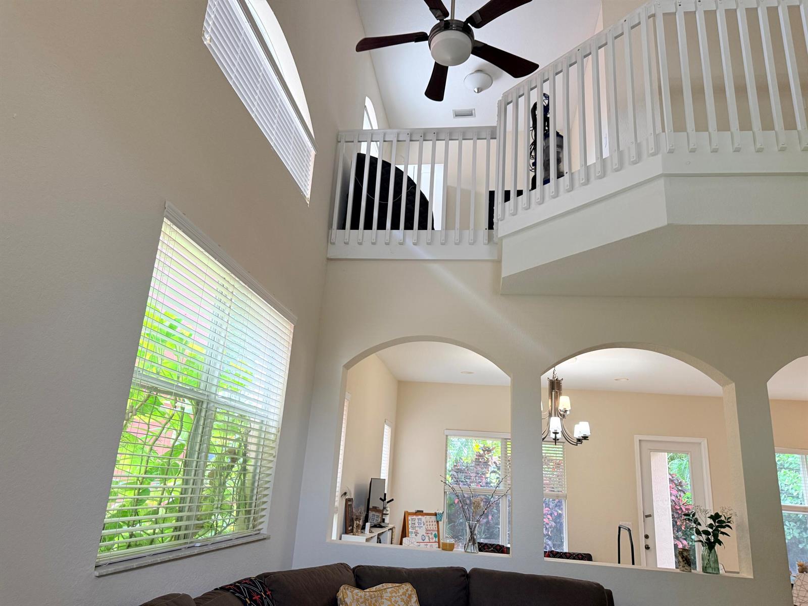 A high-ceilinged living room features a white balcony, arched wall openings, and large windows — 17 Country Lake Circle, Boynton Beach FL 33436, BOYNTON BEACH, FL