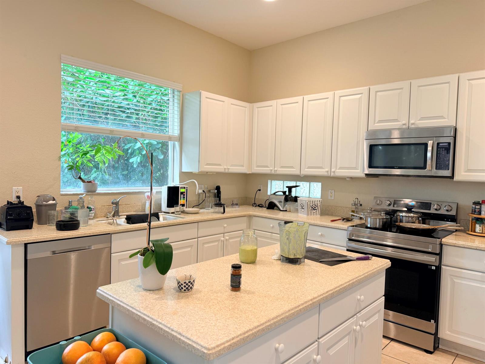 A kitchen with white cabinets, stainless steel appliances, a center island, and a window view — 17 Country Lake Circle, Boynton Beach FL 33436, BOYNTON BEACH, FL
