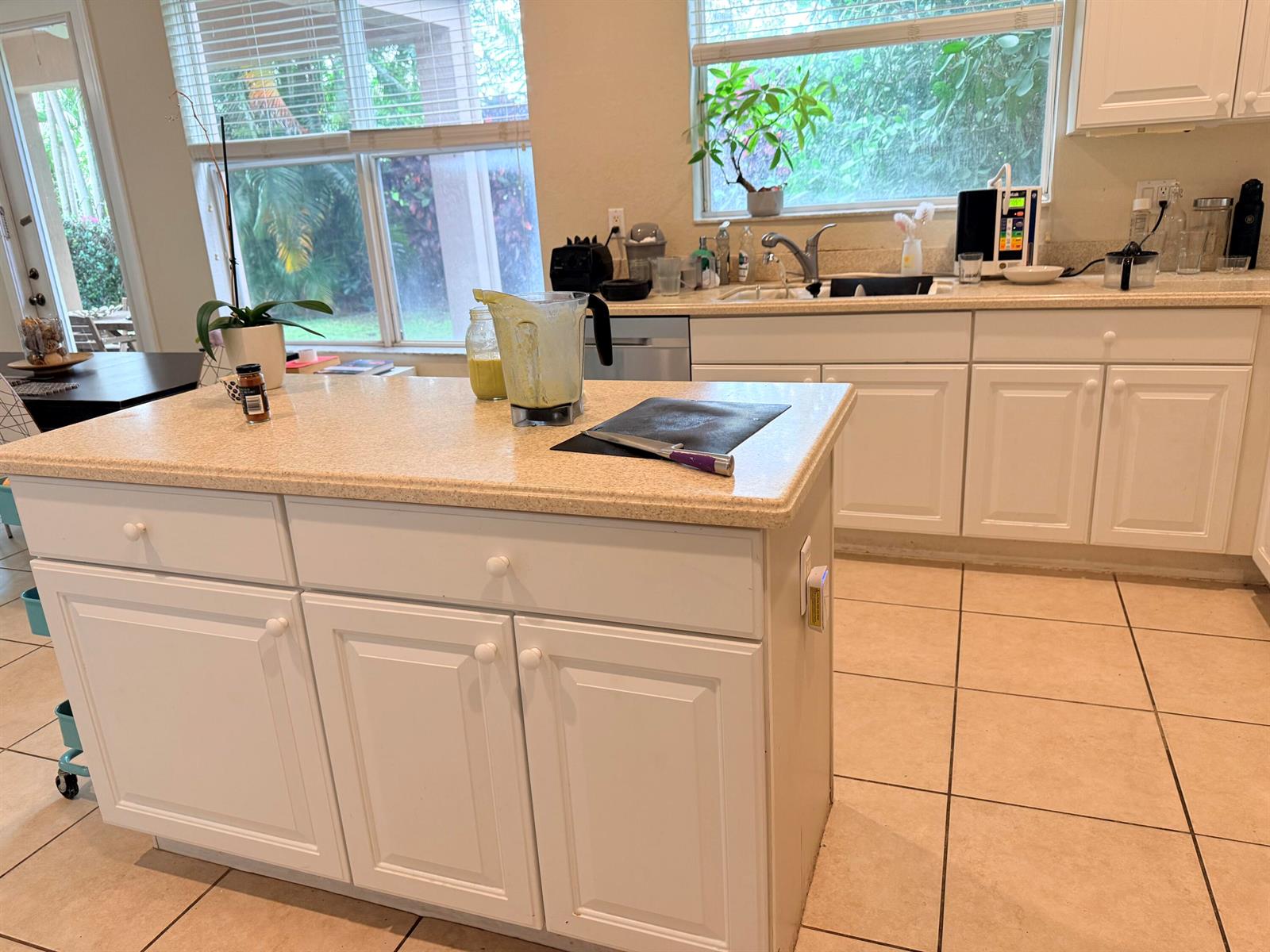 A kitchen features a central island with a speckled countertop, white cabinets, and tile flooring — 17 Country Lake Circle, Boynton Beach FL 33436, BOYNTON BEACH, FL