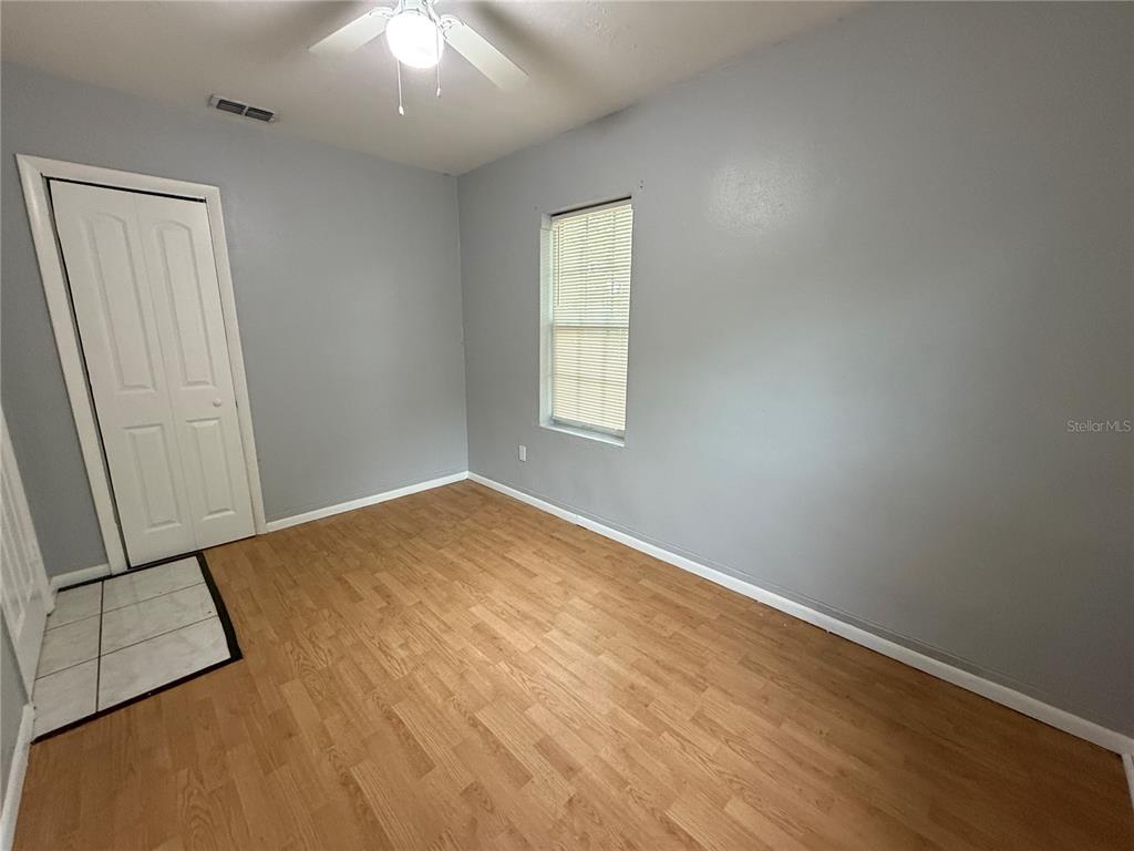 An empty bedroom features gray walls, wood-look flooring, a window with blinds, and a ceiling fan — 2705 6TH STREET W, BRADENTON, FL
