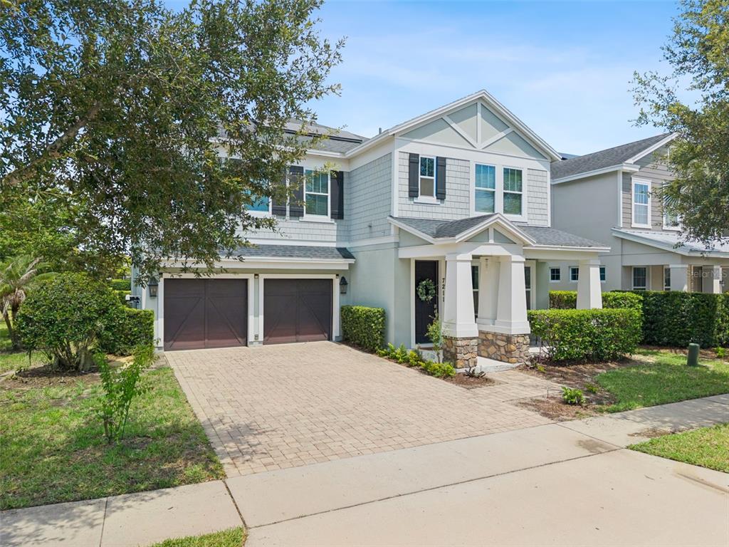 A two-story house with a light blue exterior, a two-car garage, and a paved driveway — 7211 STILL POND LANE, WINDERMERE, FL