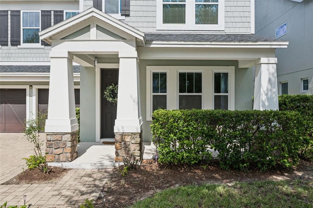 The exterior of a two-story house features a covered front porch with stone-based columns — 7211 STILL POND LANE, WINDERMERE, FL